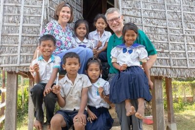 Dr. Scott Bernardy posing with happy children in front of hut with toothbrushes