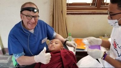 Dental volunteer and assistant help boy monk