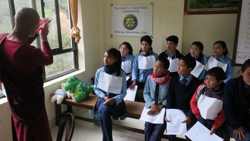 Monk teaching children in Global Dental relief clinic how to brush their teeth