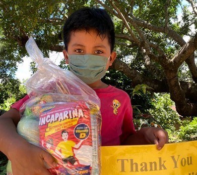 child overseas holding bag of food and thank you sign